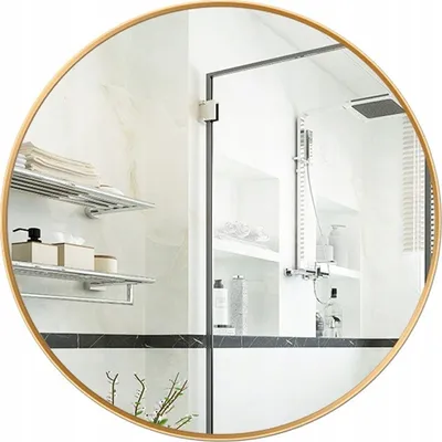 A round mirror with a golden frame reflecting a modern bathroom interior.