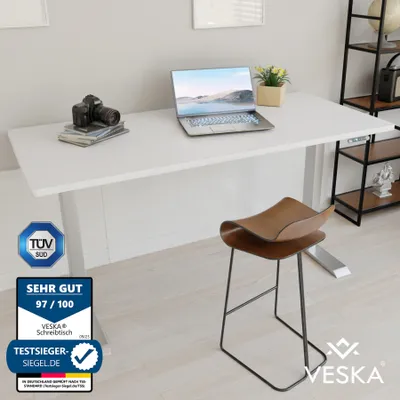 A white standing desk with a laptop, camera, and stool in a modern office setting.