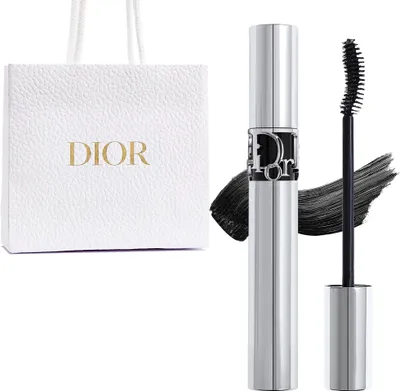 A white Dior shopping bag and a silver Dior mascara tube with black mascara.