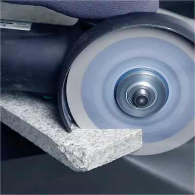 Close-up of an angle grinder cutting a piece of granite.