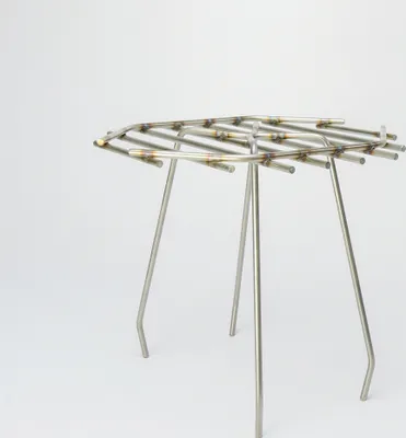 A stainless steel grate with three legs, presented against a white background.