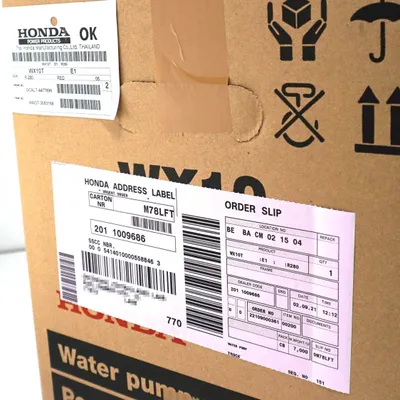 A close-up view of a cardboard box with shipping labels and markings.