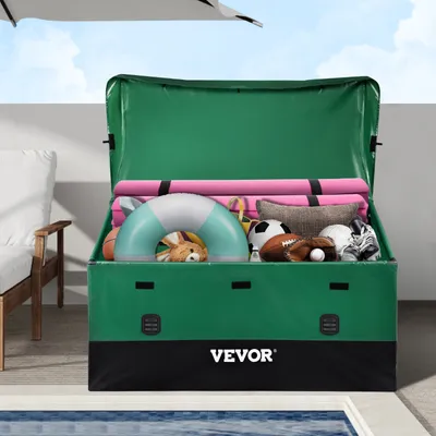 An open green storage box filled with various items like pool floats, pillows, and sports balls, placed outdoors near a pool.