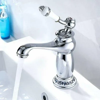 A close-up shot of a chrome faucet with a white ceramic handle, dispensing water into a white sink.