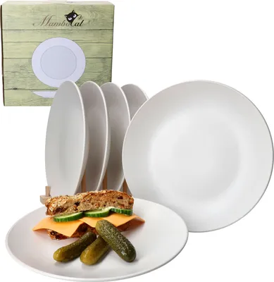A set of white plates with a sandwich and pickles on one plate, and a box in the background.