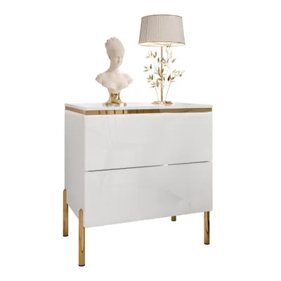 A white high-gloss nightstand with gold accents and legs, decorated with a bust and a lamp.