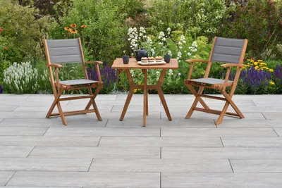 A garden setting with a bistro set and flowers.