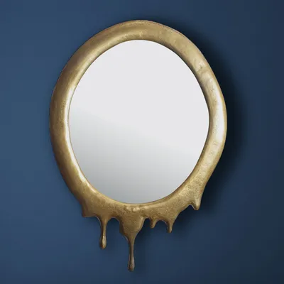 A gold oval mirror with a dripping effect frame hangs on a dark blue wall.