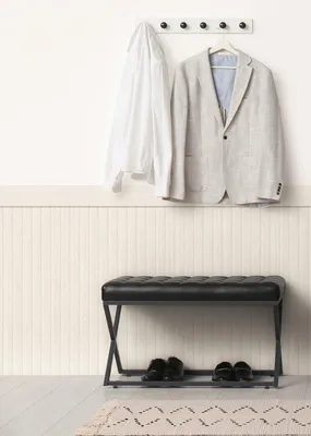 A hallway scene with a coat rack, a bench, and shoes.