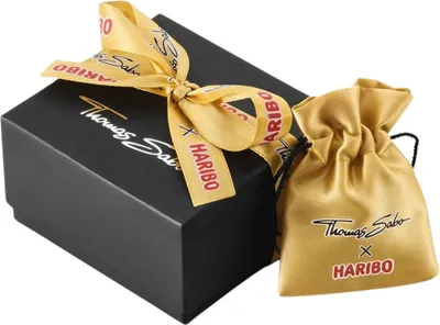 A black gift box with a gold ribbon and a gold drawstring pouch next to it.