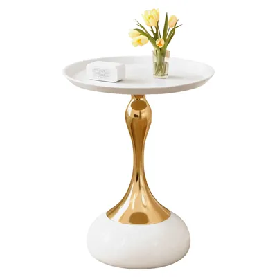 A white round side table with a gold metallic base and a vase of yellow tulips and a white object on top.