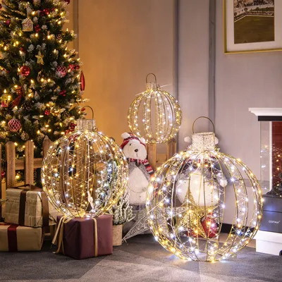 A festive Christmas scene with a decorated tree, gifts, and large illuminated decorative balls.