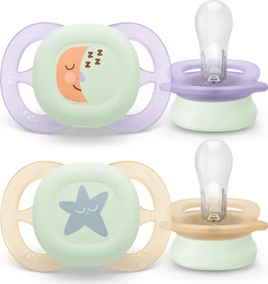 Two Philips Avent pacifiers are shown against a white background. One pacifier is purple and green with a moon design, and the other is tan and green with a star design.