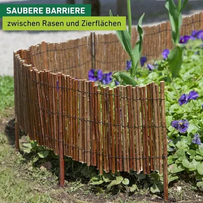 A curved willow border fence separating a lawn from a flower bed with purple flowers.