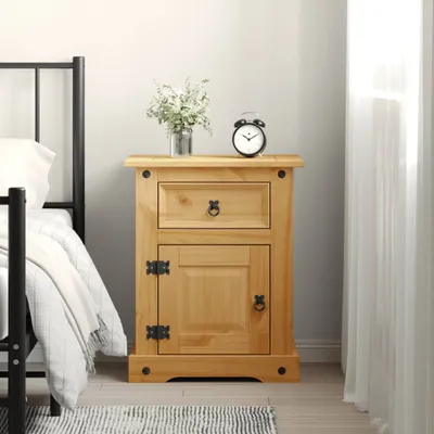A wooden nightstand next to a bed with a black metal frame. There is a vase of flowers and an alarm clock on top of the nightstand.