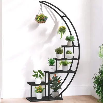 A black metal plant stand with multiple tiers, holding various potted plants, against a white wall.
