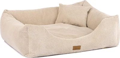 A beige dog bed with a raised rim and a small pillow inside, set against a white background.