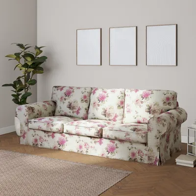 A floral-patterned sofa in a living room setting with a plant and framed pictures on the wall.