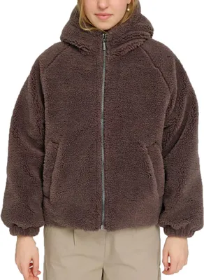 A woman is wearing a brown faux-fur hooded jacket.
