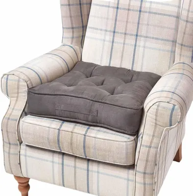 A close-up of a grey cushion placed on a checkered armchair.