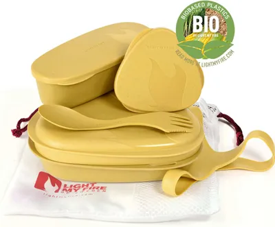 A set of yellow camping meal containers and utensils, neatly arranged on a white cloth bag.
