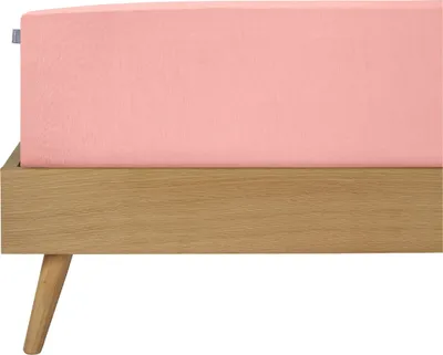 A close-up view of a pink fitted sheet on a wooden bed frame.