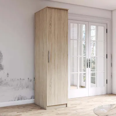 A tall, narrow cabinet with a light wood grain finish is placed against a wall with a decorative mural and next to a set of double doors. The floor is made of light wood planks.
