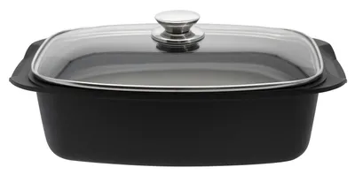 A black roasting pan with a glass lid and a silver handle, shown from a side-angle.