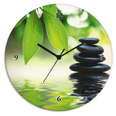 A clock with a zen stone pyramid on a water surface.