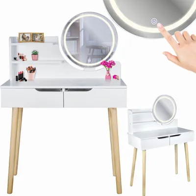 A white dressing table with wooden legs and a round LED mirror, decorated with makeup and a small vase of flowers.