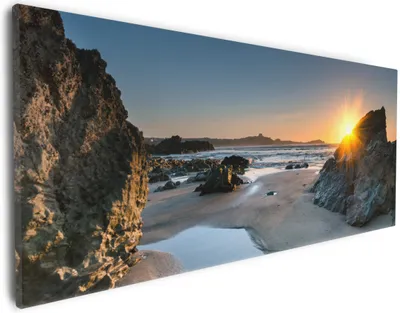 Produktbild von Wallario Premium Leinwandbild Sonnenuntergang hinter einem Felsen am Strand in Größe 30 x 75 cm