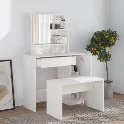 A white vanity table with a mirror and a stool, set against a light gray background. A potted plant with yellow fruit is visible to the right.