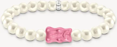 A bracelet with pearls and a gummy bear charm on a white background.