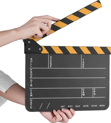 A hand holding a film clapperboard.