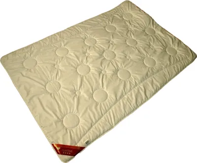 A cream-colored duvet with circular quilting is laid out on a white background.