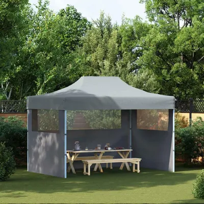 A party tent set up in a garden with a picnic table and benches inside.