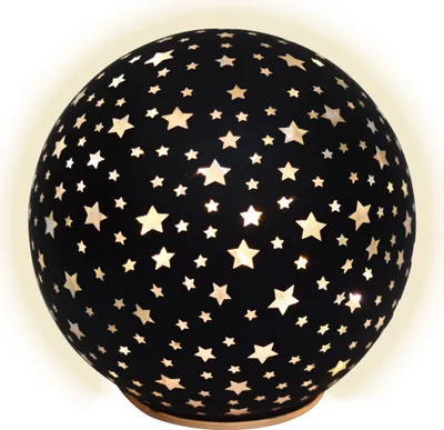 A black spherical lamp with cut-out star shapes, illuminated from within, resting on a light-colored base.