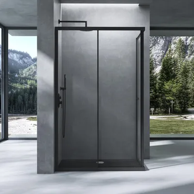 A modern shower cabin with a black frame and glass doors, set against a backdrop of a concrete wall and a large window overlooking a mountainous landscape with pine trees.