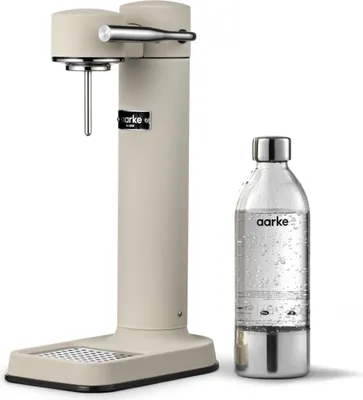 A sand-colored Aarke Carbonator 3 soda maker with a clear PET bottle filled with water.