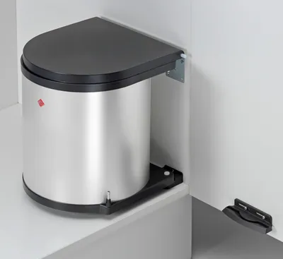 A corner trash can with a black lid and silver body, mounted inside a cabinet.