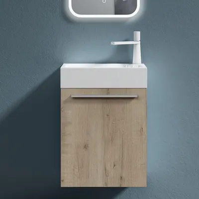 A modern bathroom vanity with a white sink and a wood-grain cabinet against a blue wall.