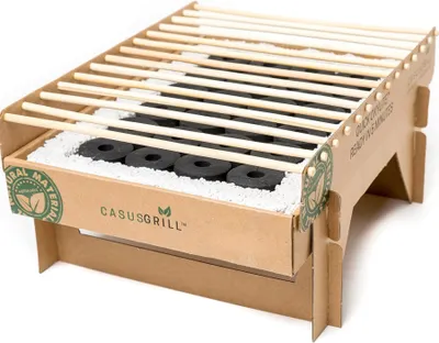 A disposable cardboard grill with charcoal and wooden grates, set against a white background.