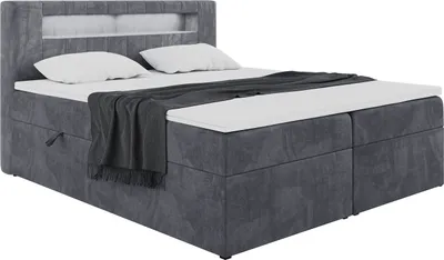 A dark gray upholstered boxspring bed with a headboard featuring LED lighting, two pillows, and a dark gray throw blanket.