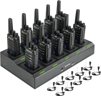A set of walkie-talkies and their charging station, with additional headsets shown in the foreground.