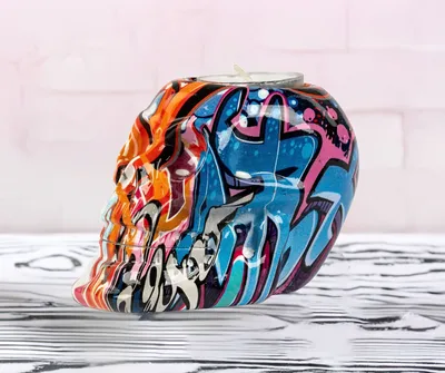A skull-shaped teacup holder with graffiti art.