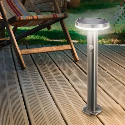 A solar-powered garden light is shown on a wooden deck next to a lounge chair.