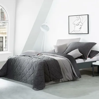 A bedroom setting with a bed, lamp, and artwork.