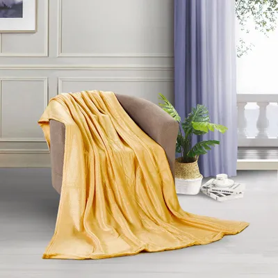 A golden yellow blanket draped over a chair in a room with a window and curtains.