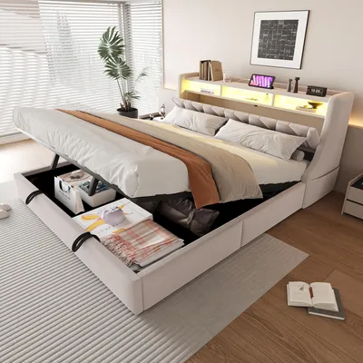 A bedroom scene featuring a hydraulic storage bed with its storage compartment open, revealing stored items. The bed is made up with bedding and pillows, and the headboard has integrated lighting.