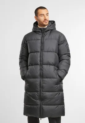 A man wearing a long black puffer jacket.